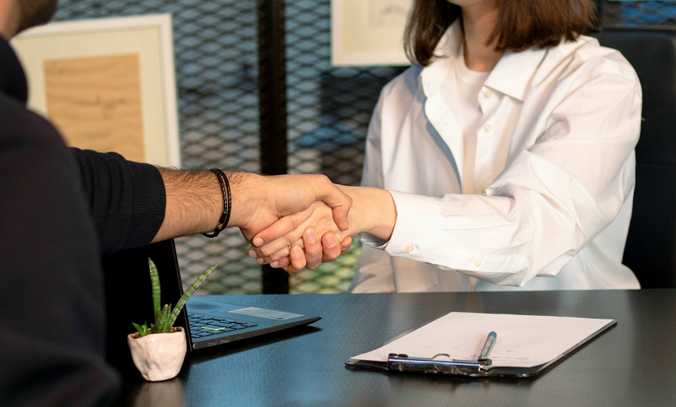 Zwei Personen reichen sich die Hand in einem professionellen Gespräch – Symbolbild für Bewerbung oder Auswahlgespräch im Medizinstudium.