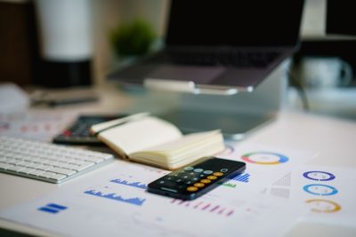 Offener Laptop auf einem modernen Schreibtisch mit aufgeklapptem Notizbuch, Taschenrechner, Tastatur und ausgedruckten Grafiken – Punktzahl des TMS verstehen