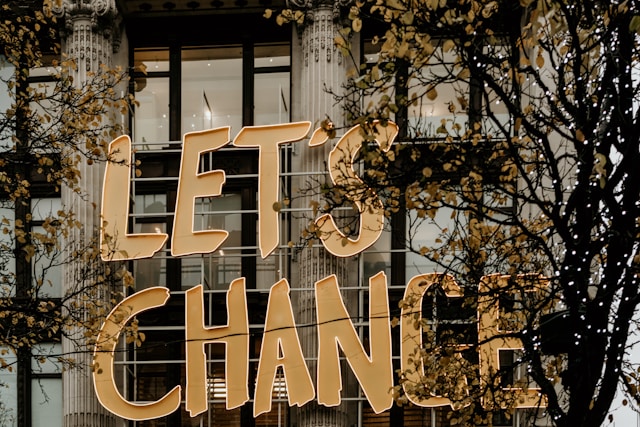 Leuchtende Lettern „LET’S CHANGE“ vor klassischer Uni-Fassade – symbolisch für die neue Gewichtung des TMS bei der Studienplatzvergabe an vielen medizinischen Hochschulen 2025.