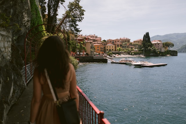 Studentin blickt auf ein mediterranes Küstenstädtchen am Wasser.